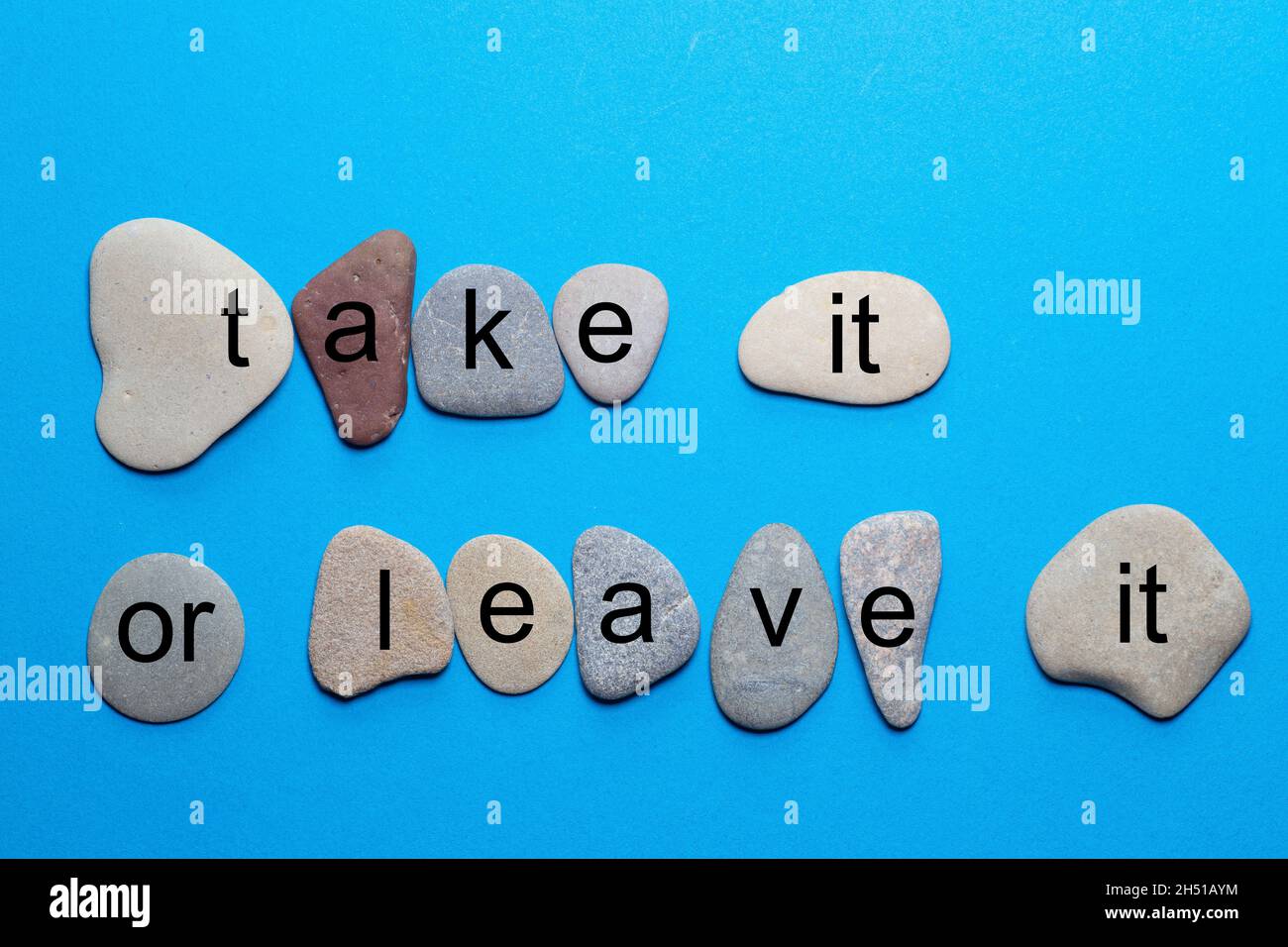 La frase prendere o lasciare che si trova come singole lettere su pietre naturali lisce con colori più naturali su uno sfondo blu Foto Stock