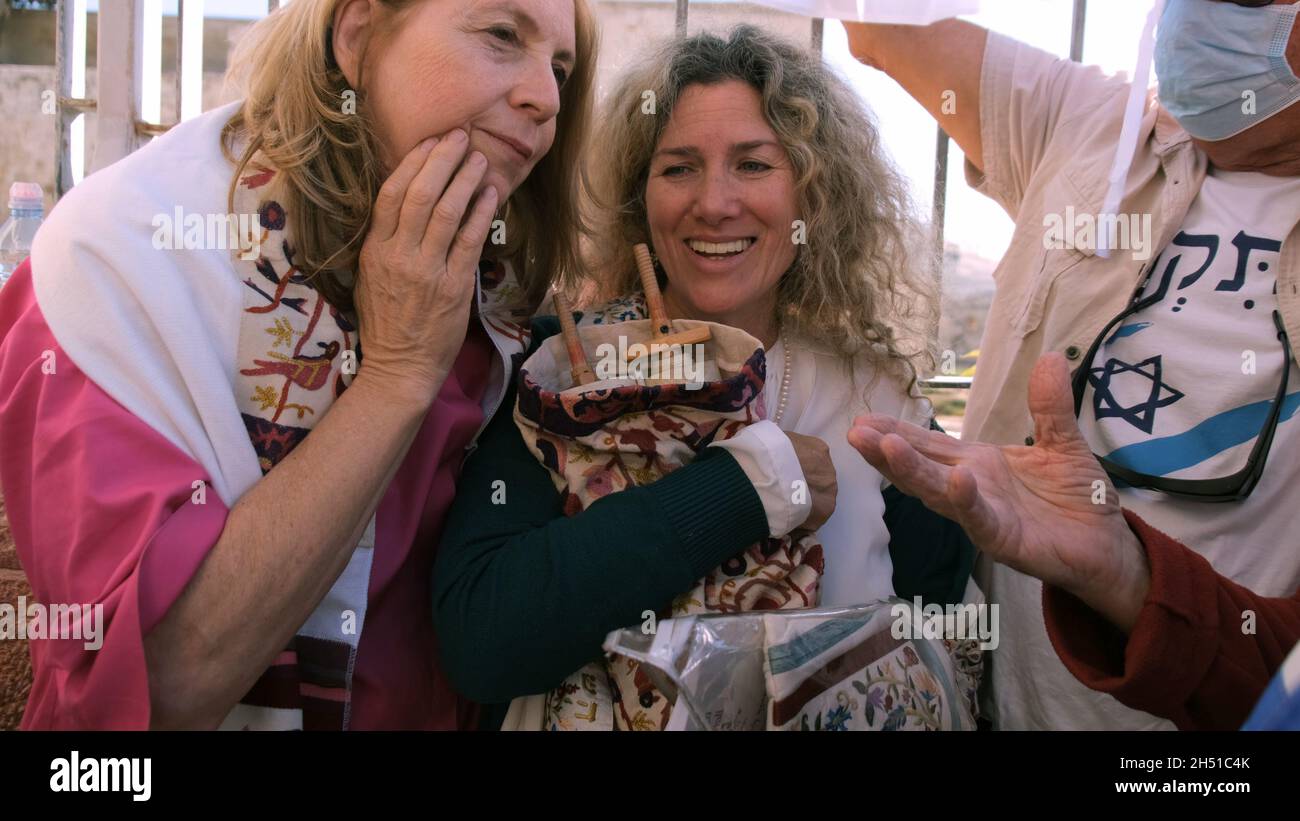 Un membro delle Donne del Muro tiene un rotolo di Torah, mentre le forze di sicurezza trattengono gli ebrei ultraortodossi che protestano contro la loro preghiera al Muro occidentale il 05 novembre 2021 a Gerusalemme, Israele. Le Donne del Muro sono un gruppo di preghiera femminista che tiene una sessione di preghiera mensile al Muro occidentale e hanno costantemente sostenuto che non esiste un'unica "consuetudine del luogo” e che il loro diritto di pregare è una libertà religiosa sancita dalla legge israeliana Foto Stock