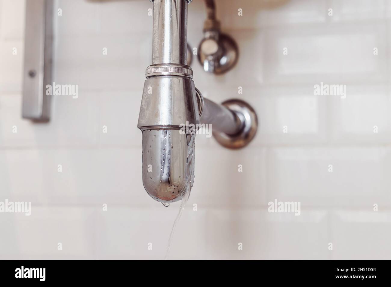 Perdita d'acqua dal sifone moderno in acciaio in bagno. Problemi con la guarnizione. Foto Stock