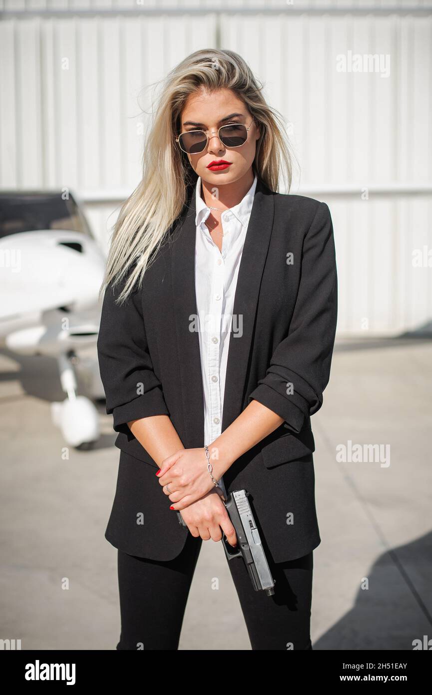 Bella ragazza spy agente professionale bodyguard posa con pistola. Donna della polizia di sicurezza in abito nero civile. Chiudere la protezione di sicurezza Foto Stock