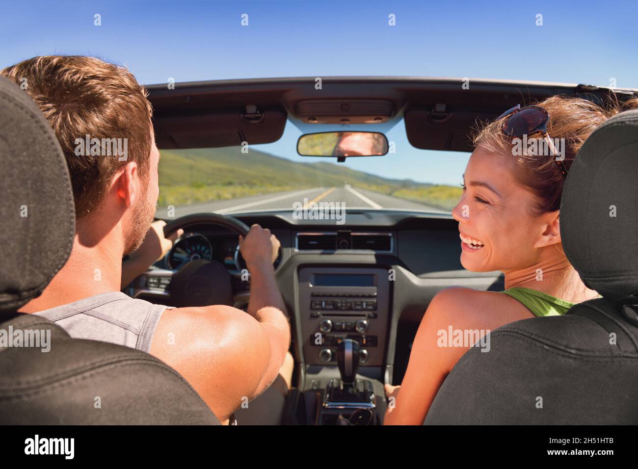 Viaggio di strada vacanza coppia guida auto convertibile in estate viaggio vacanza divertimento. Ridendo ragazza asiatica con uomo conducente. Foto Stock