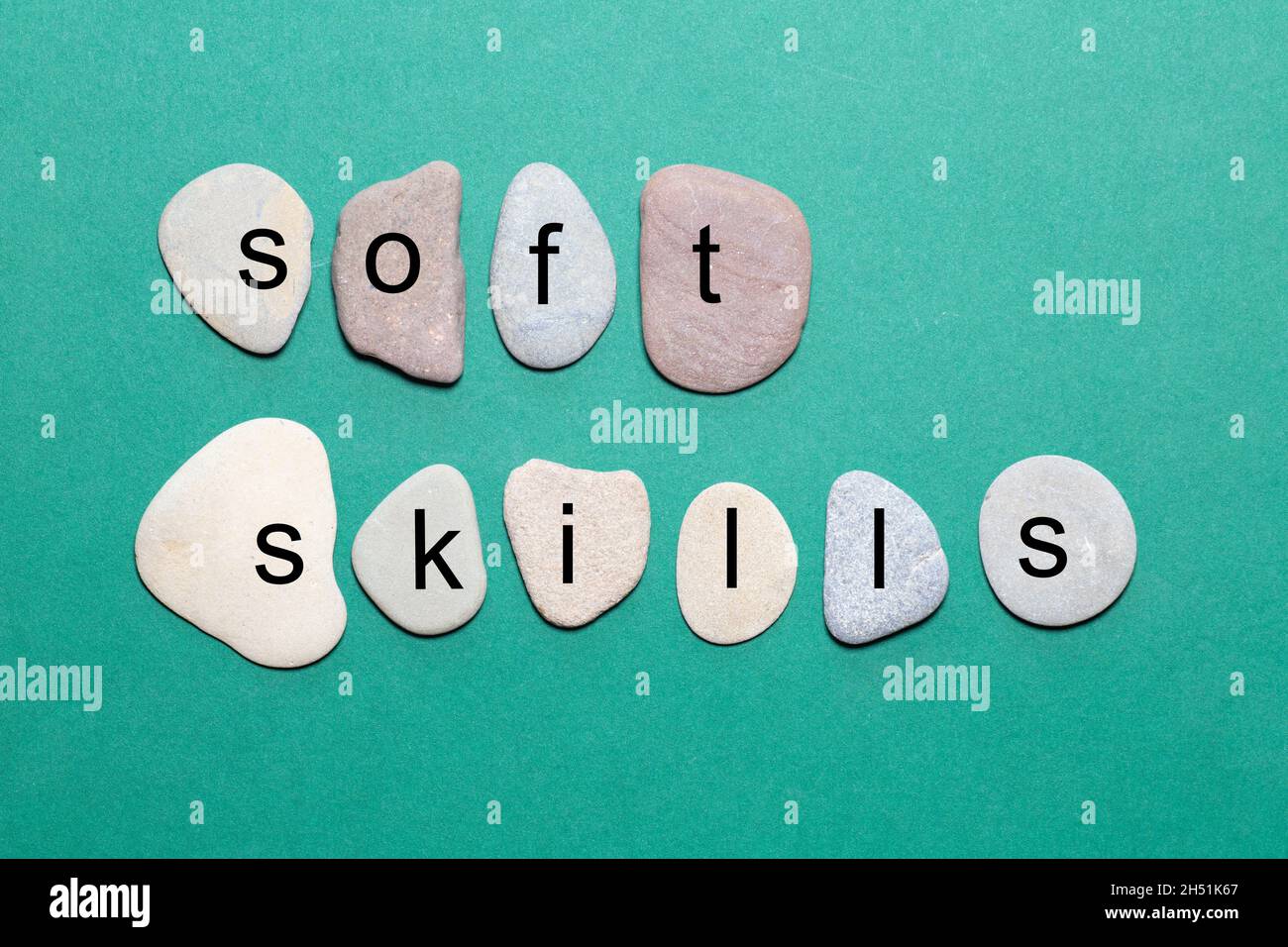 Il termine soft skills si trova come lettere singole su pietre naturali lisce con colori più naturali su sfondo verde Foto Stock