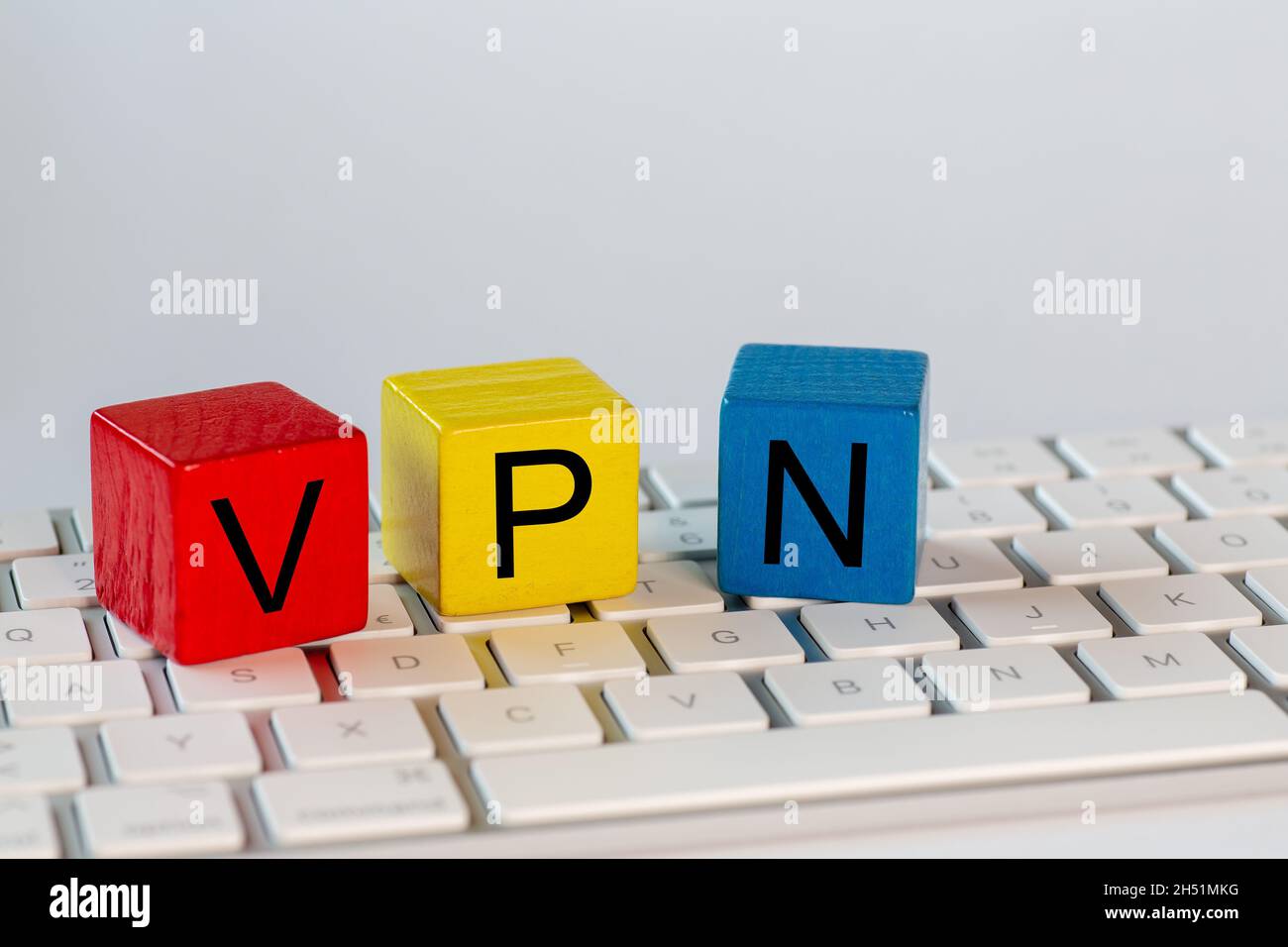 Blocchi colorati con le lettere VPN che stanno per rete privata virtuale. I blocchi sono su una tastiera luminosa del computer e isolati con bac bianco Foto Stock