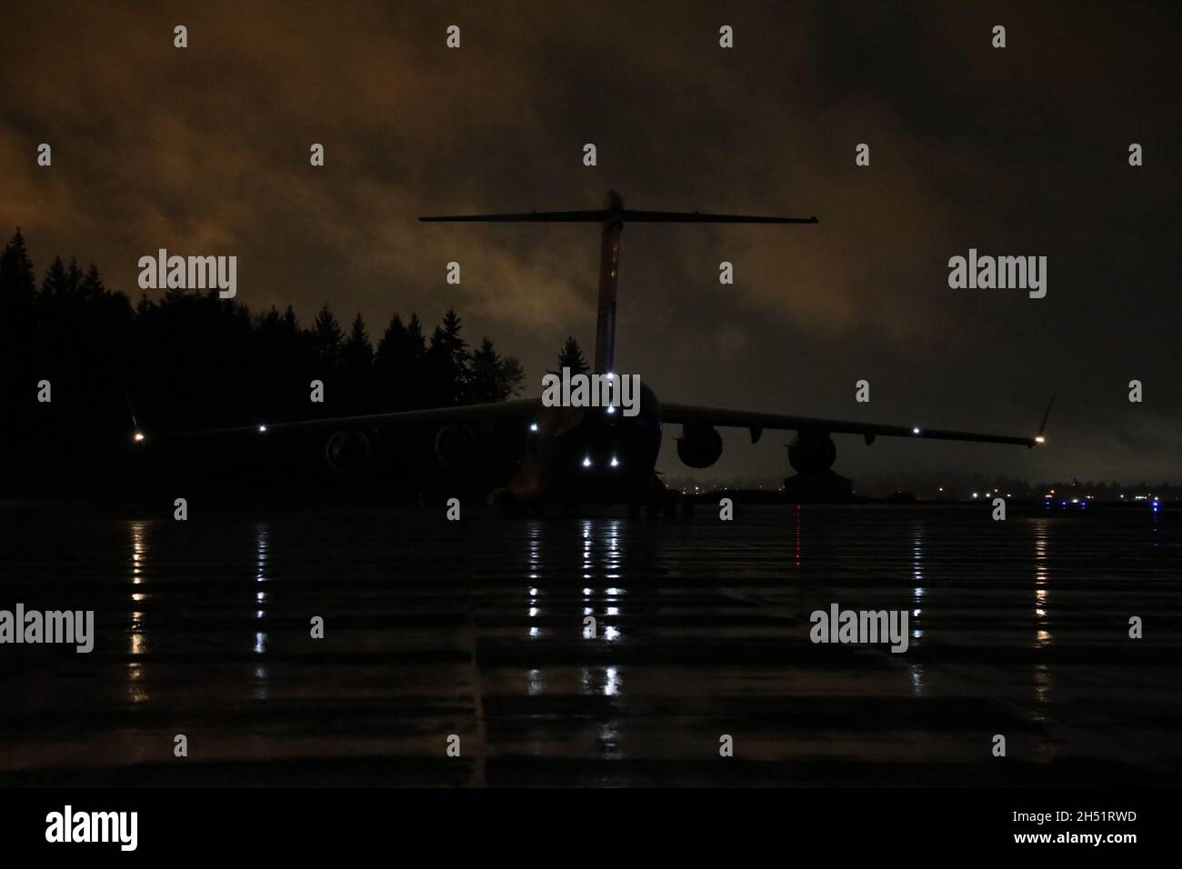 Un C-17 Globemaster III parcheggiato sulla linea del flightline di notte durante l'esercitazione Rainier Guerra 21B alla base congiunta Lewis-McChord, Washington, 3 novembre 2021. Rainier War 21B esercitò e valutò la capacità dell'ala di impiegare la forza e la loro capacità di eseguire durante le operazioni di guerra e/o di emergenza in un ambiente ad alta intensità, contestato in tempo di guerra, degradato e operazionalmente limitato, sostenendo le operazioni di emergenza contro un avversario vicino-peer nell'area di responsabilità del comando dell'Indo-Pacific degli Stati Uniti. (STATI UNITI Air Force foto di Senior Airman Christopher Sommers) Foto Stock