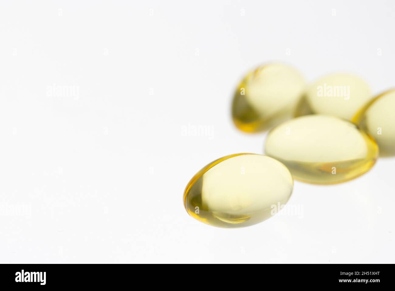 Raggruppamento di più linguette di gel di olio di pesce, vitamina D o e supplementi su un fondo bianco morbido con spazio di copia Foto Stock