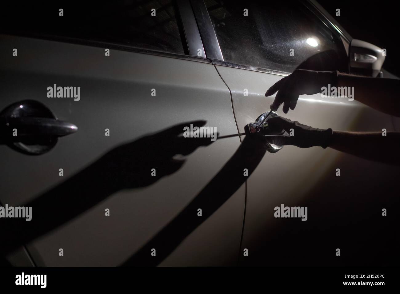Ladro di auto utilizzando uno strumento per rompere in una macchina Foto Stock