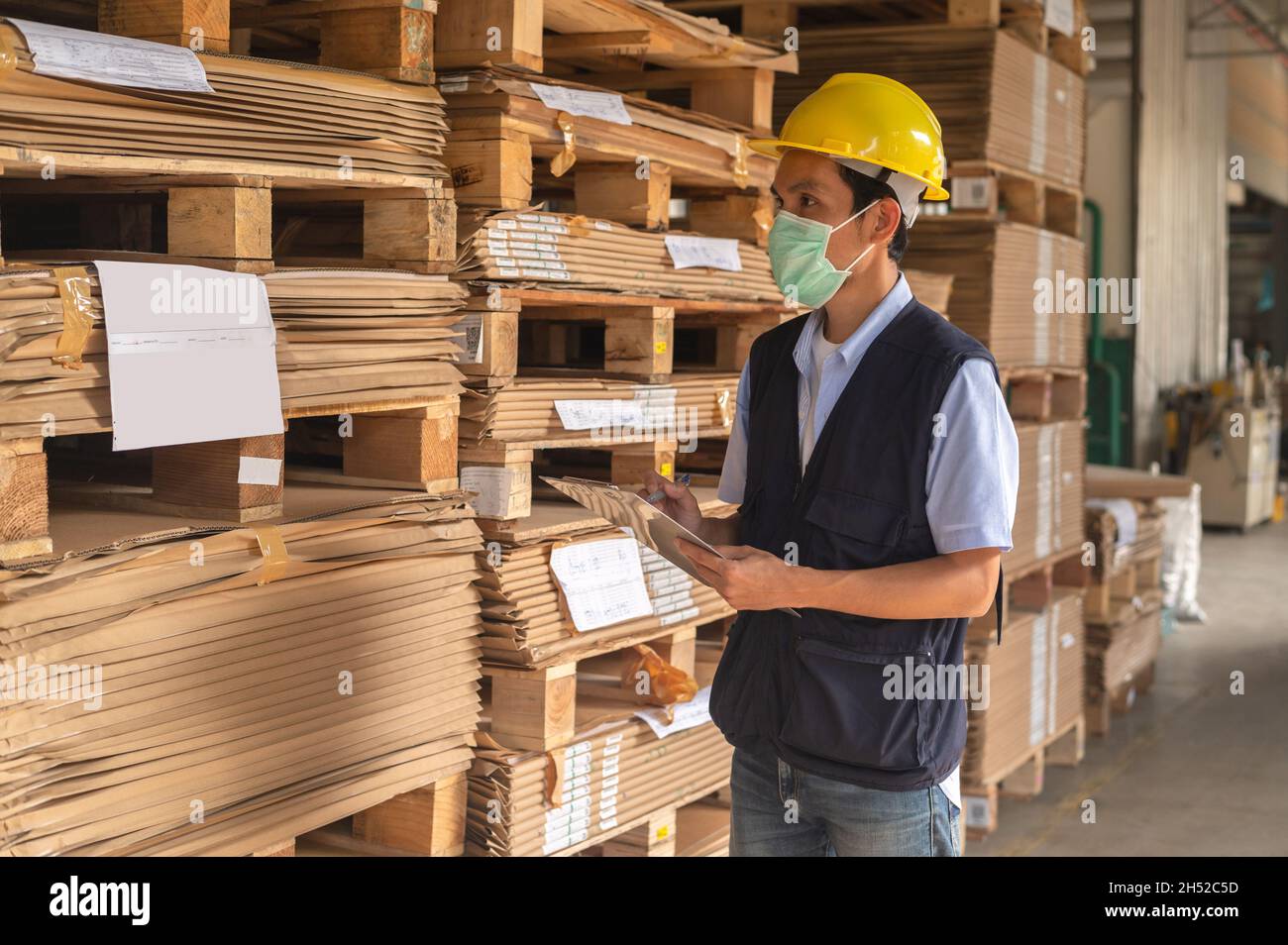 Lavoratore che controlla l'inventario delle materie prime in fabbrica Foto Stock