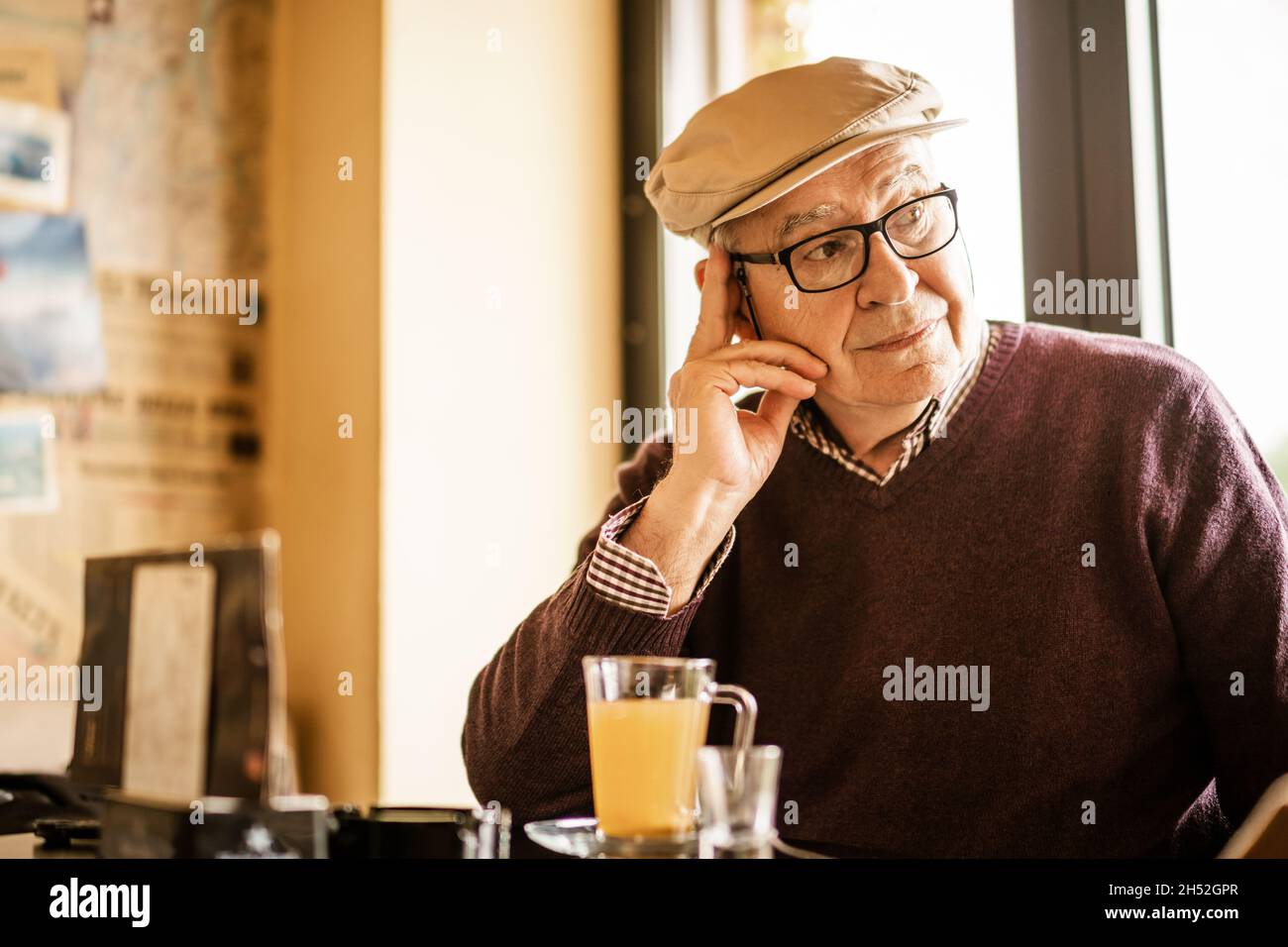 L'uomo anziano è seduto in un caffè e beve il tè. È pensivo. Foto Stock