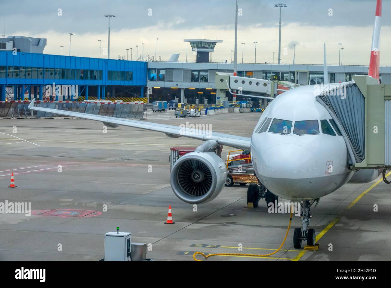 Giorno nuvoloso all'aeroporto moderno. L'aereo è dotato di un ponte jet per l'imbarco e lo sbarco dei passeggeri Foto Stock