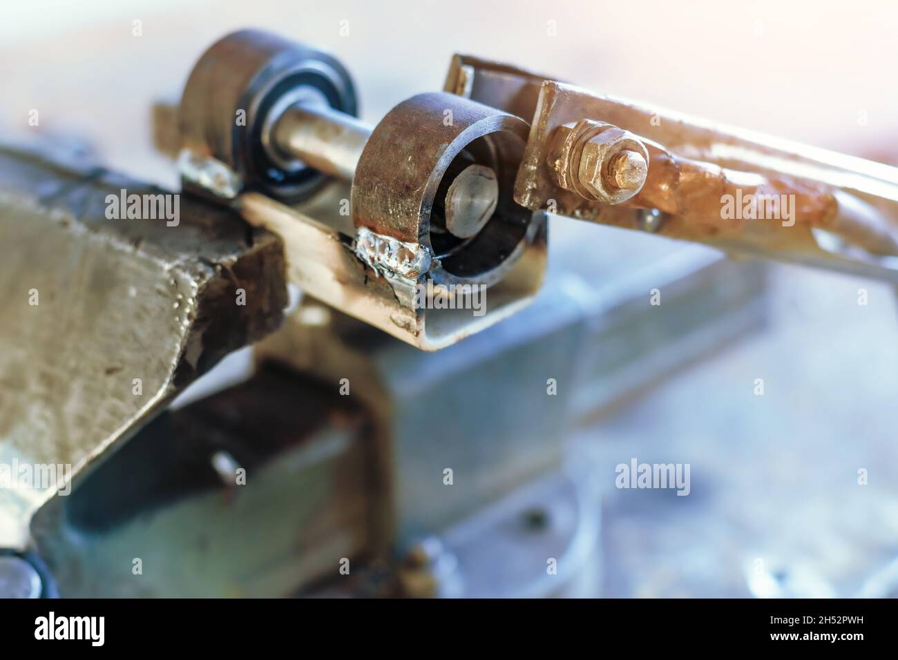 Il prodotto metallico viene schiacciato in una morsa sul luogo di lavoro dell'officina. Banco da lavoro con vecchie visse. Foto Stock