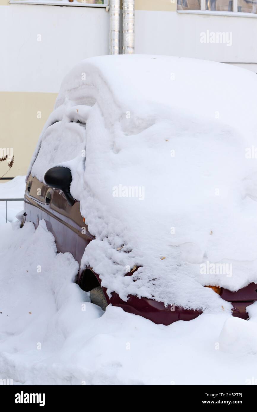 auto abbandonata rossa in inverno parcheggiata sotto un grande strato di neve in un giorno luminoso e soleggiato geloso Foto Stock