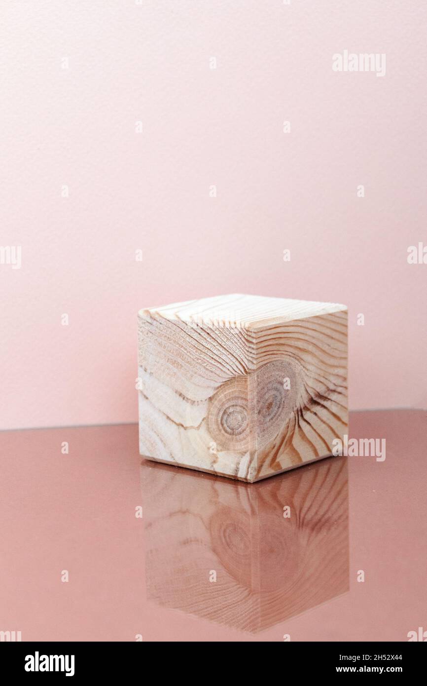 cubo di legno con riflessione a specchio, sfondo rosa Foto Stock