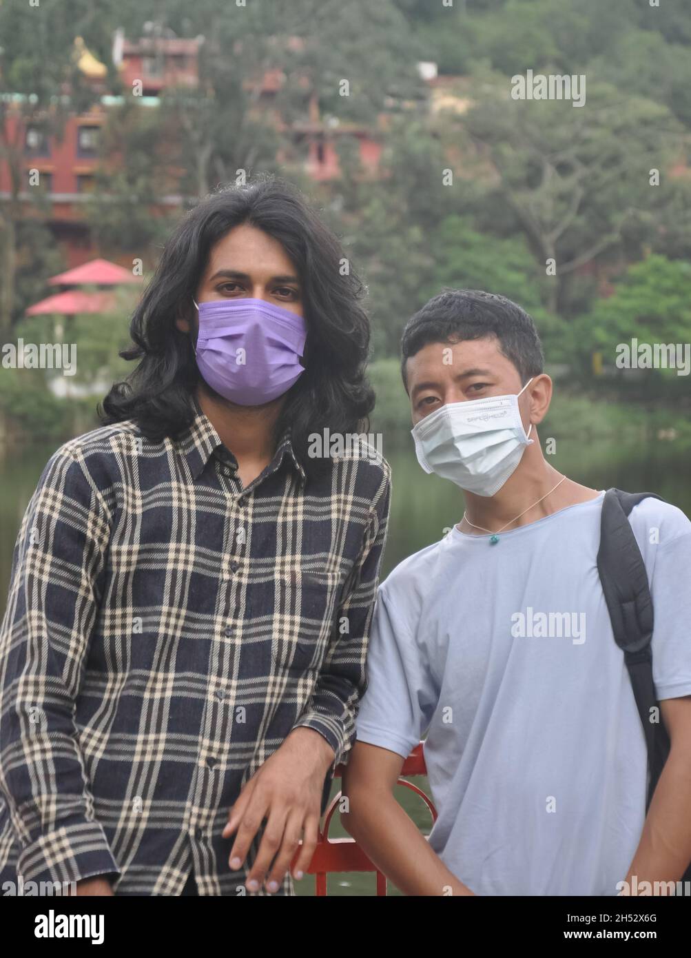 Due amici maschi con maschera che indossa in piedi fuori con guardare la fotocamera Foto Stock