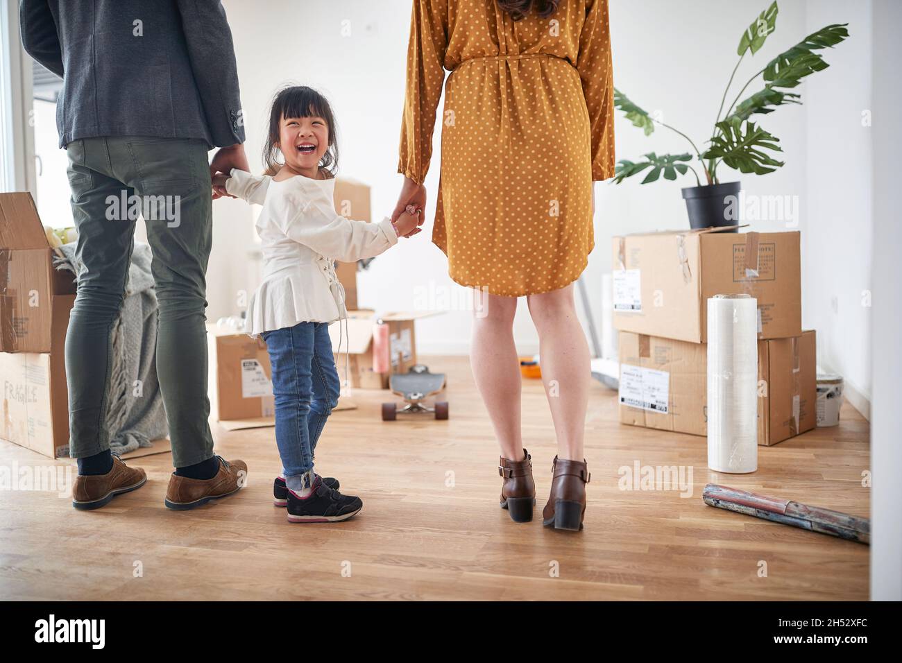 Una figlia piccola è eccitato mentre con i suoi genitori esplorano la nuova sede in un'atmosfera piacevole in cui la famiglia ha appena spostato dentro. Casa, famiglia, in movimento Foto Stock