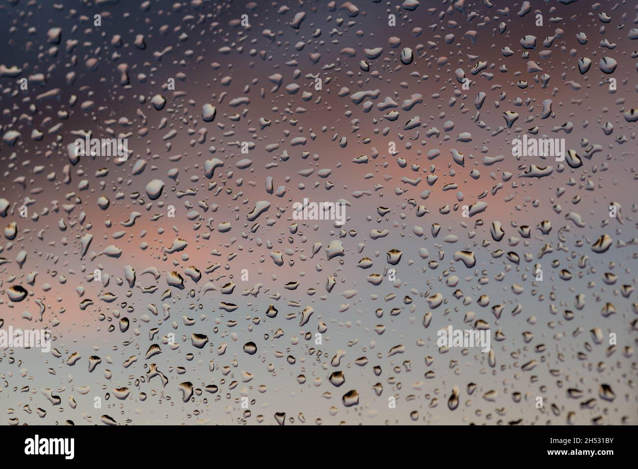 Dopo la pioggia. Il vetro della finestra è coperto all'esterno con gocce d'acqua. Sullo sfondo ci sono nuvole scure. Foto Stock