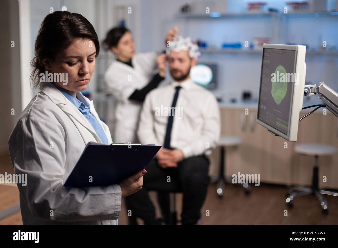 Neurologo medico donna regolazione eeg cuffia monitoraggio dell'attività cerebrale del paziente durante l'esperimento medico in laboratorio moderno. Ingegnere scienziato che analizza il sistema nervoso Foto Stock