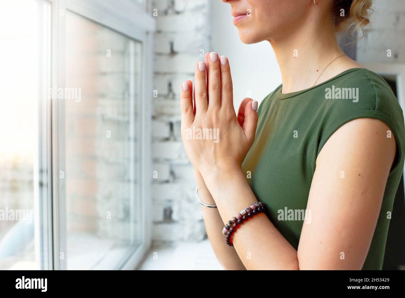 Le ragazze in una T-shirt verde, in una posa yoga in primo piano, hanno piegato i palmi insieme sul petto Foto Stock