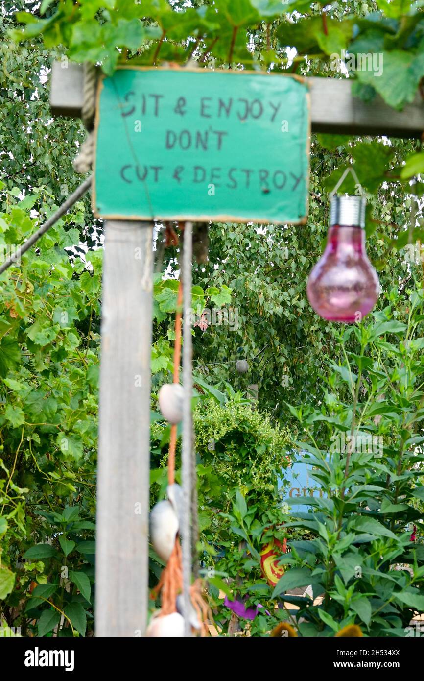 Siediti e goditi non tagliare e distruggere, testo a bordo in giardino di assegnazione Foto Stock