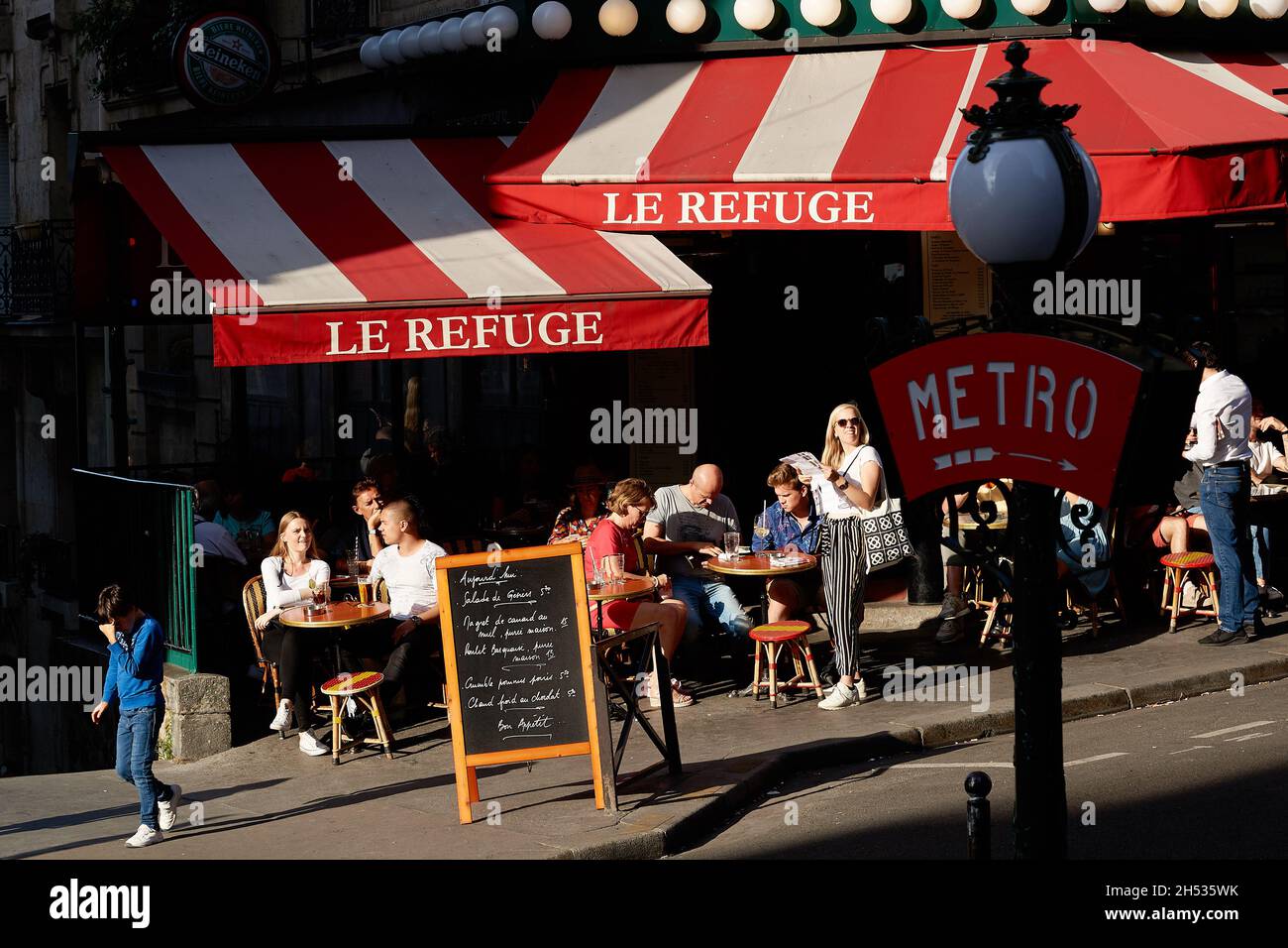 Parigi, Francia - Luglio 2019: francesi che bevono all'ombra della terrazza del ristorante le Refuge, di fronte a Lamarck-Caulaincourt metro Foto Stock