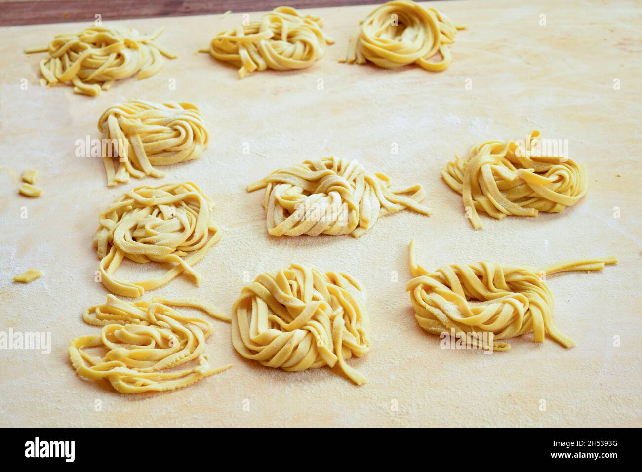 tagliatelle all'uovo fatte a mano, fatte a casa su un panello di legno Foto Stock