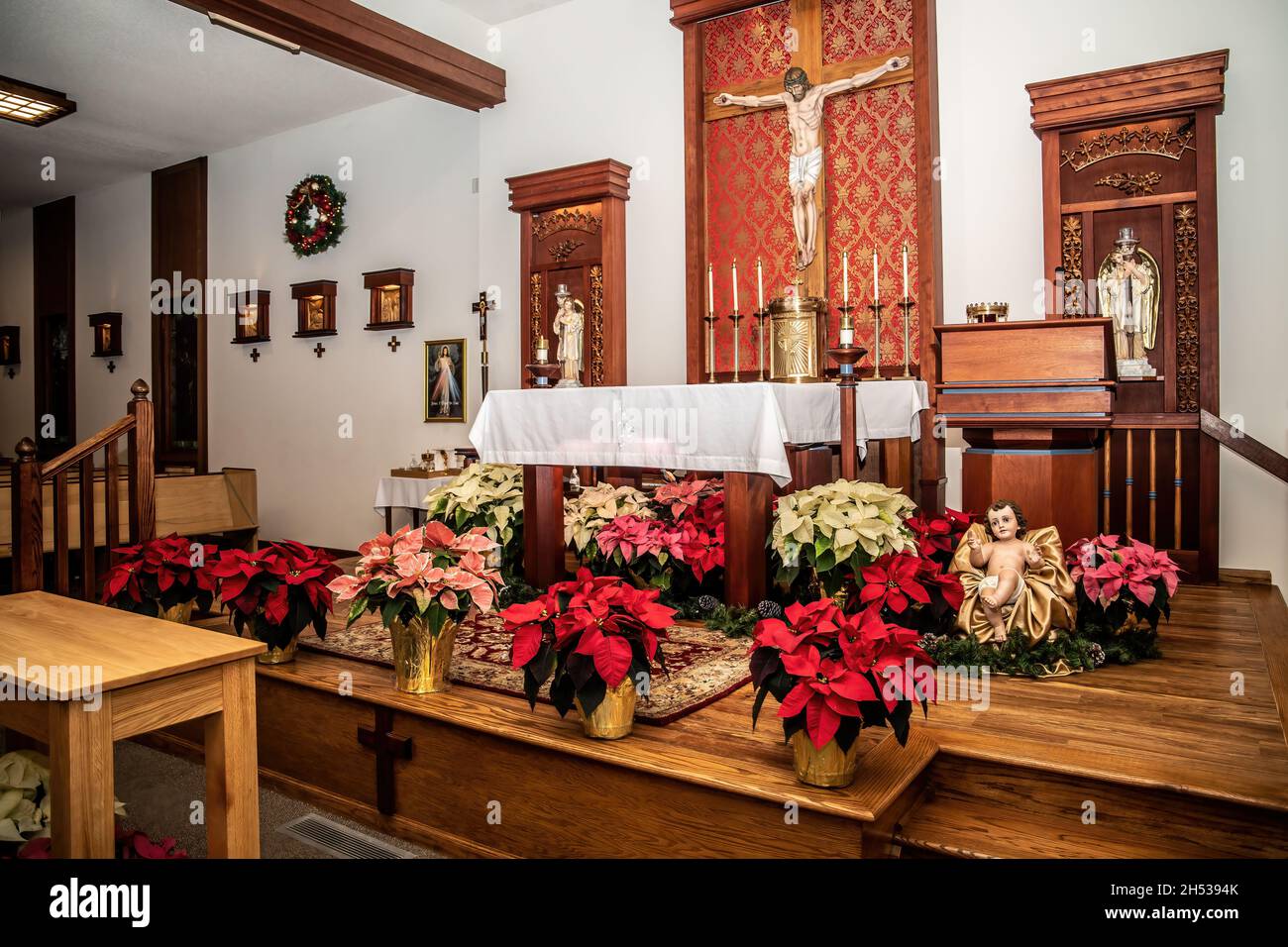 Chiesa cattolica di San Giuseppe decorata con poinsettias e il bambino Gesù intorno all'altare il giorno di Natale. Foto Stock