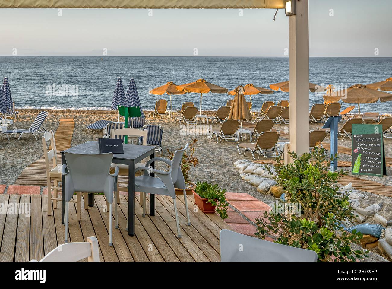 Un tavolo per due in una taverna greca che sovrastano la spiaggia e l'azzurro Mar Mediterraneo, Creta, Grecia, 11 ottobre 2021 Foto Stock