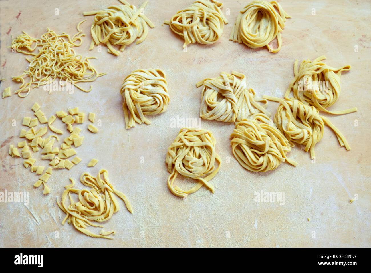 varietà di pasta fatta a mano a casa su un pannello di pasticceria in legno Foto Stock