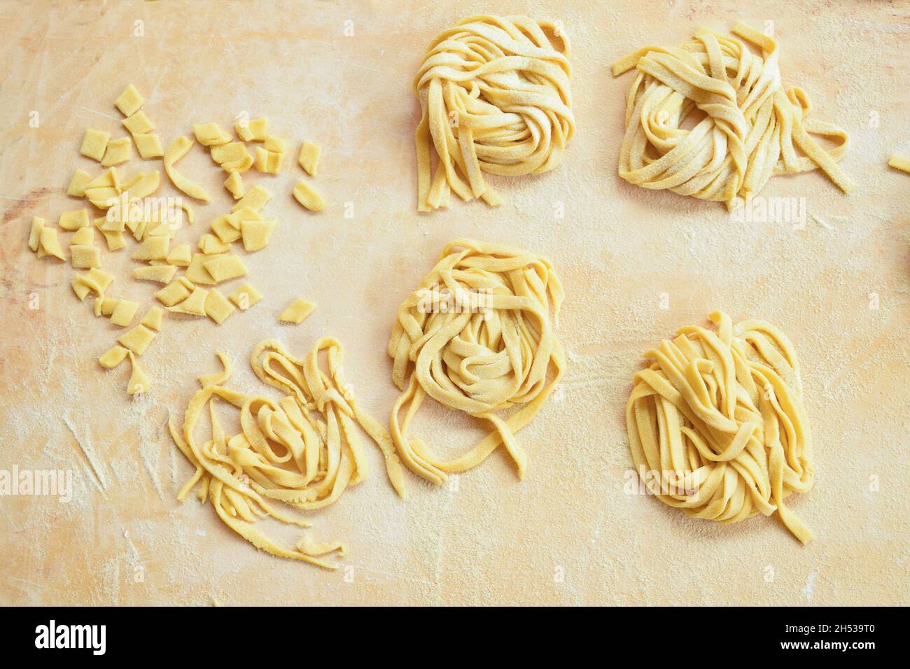 pasta di uova di varietà fatta a mano a casa su un pannello di pasticceria in legno Foto Stock