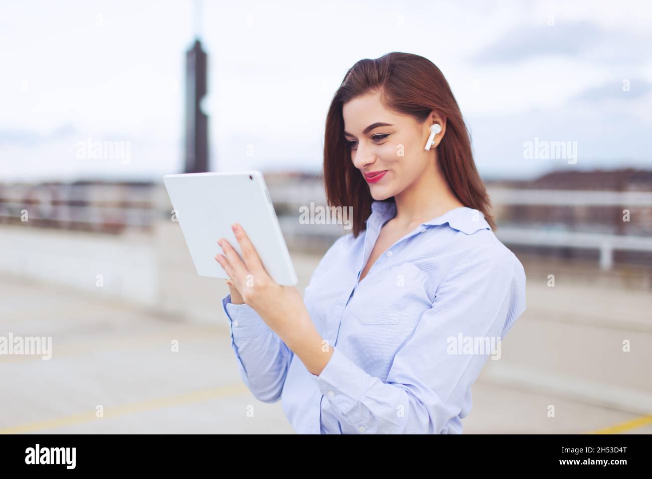 Donna operatrice caucasica giovane donna con colletto bianco e testa rossa con dispositivo a mani libere che usa il tablet all'aperto Foto Stock
