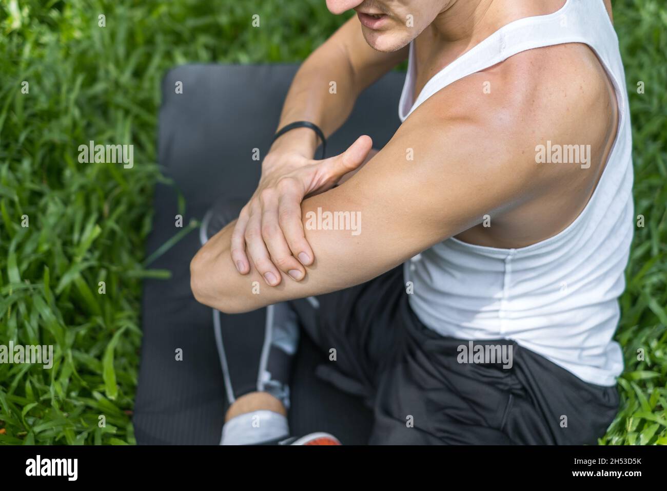 Primo piano ritratto di uomo che tocca il braccio con la mano. Uomo ferito muscoli sul suo braccio. Giovane sportivo e attivo in abbigliamento sportivo. Muscle Fit uomo Foto Stock