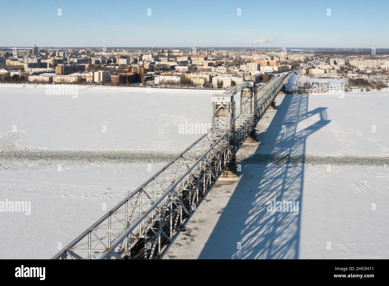 Arkhangelsk, Russia - 11 marzo 2021:la vista dall'alto in inverno sul ponte di ferro e una città attraverso il fiume ghiacciato. Foto Stock