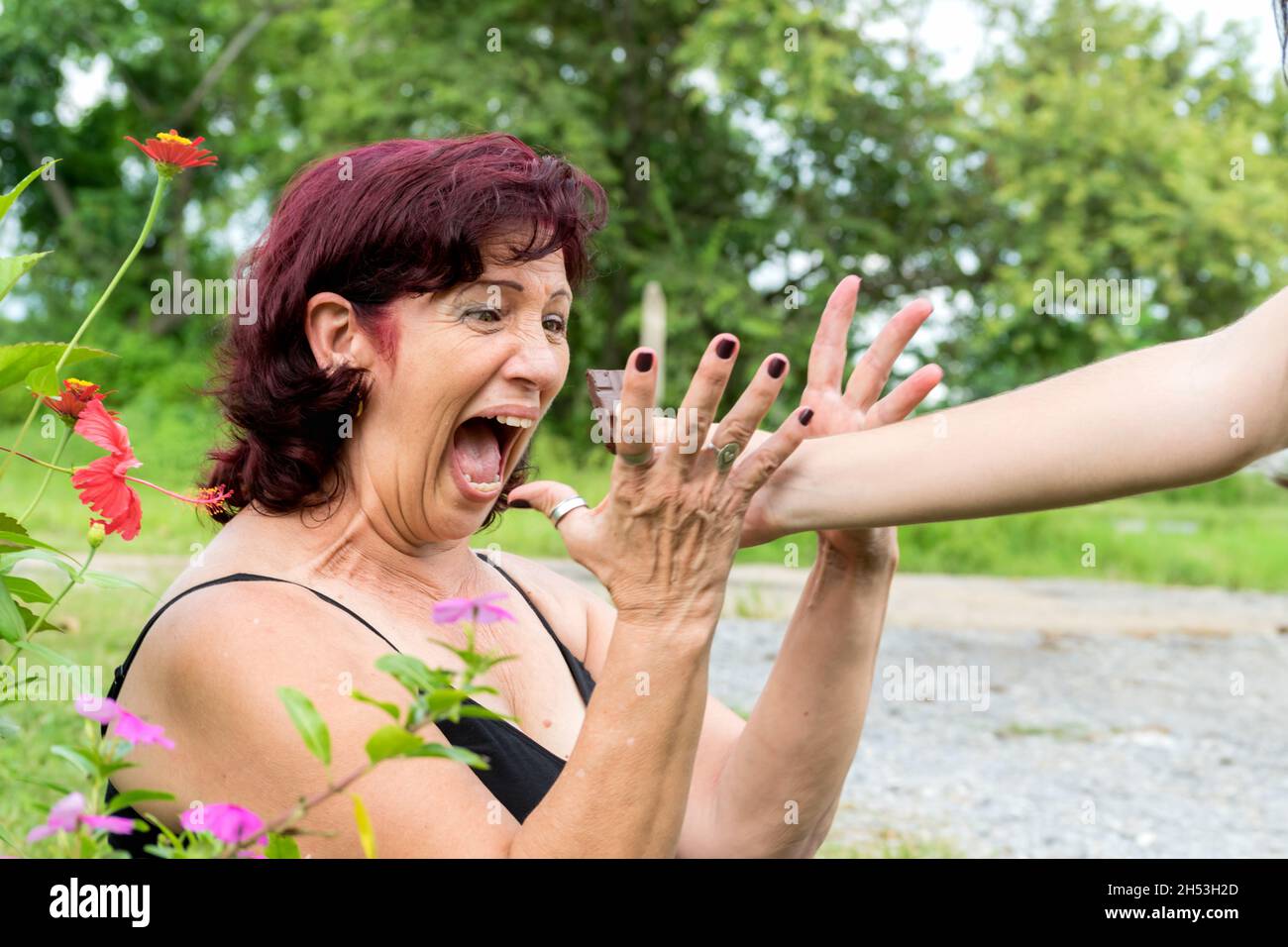 Una donna latina cresciuta che è stata veramente sorpresa da qualcuno che le offre un pezzo di cioccolato, la sua bocca è larga Foto Stock