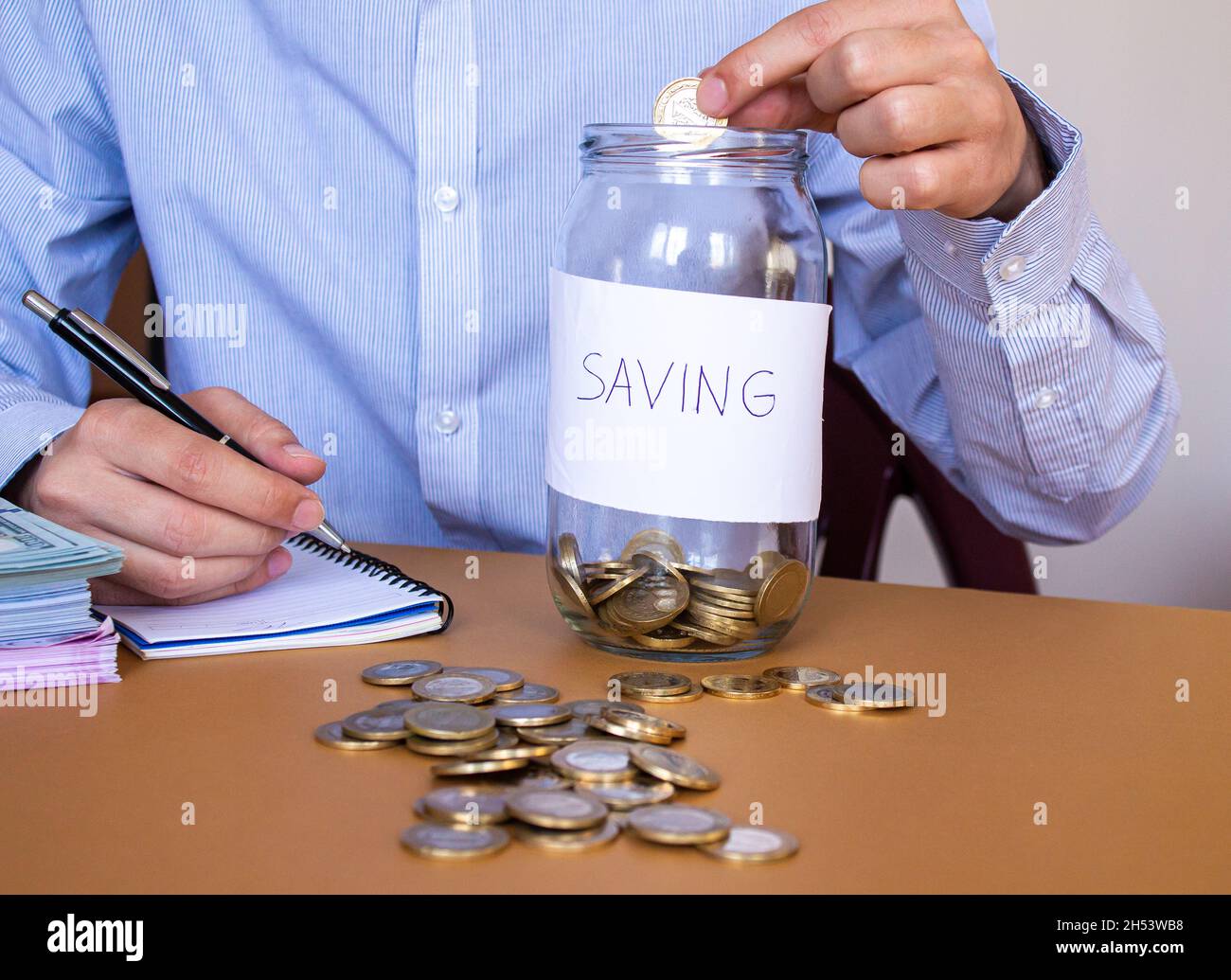 L'uomo d'affari mette le monete di soldi nel vaso di vetro, risparmiando i soldi e concetto di contabilità di finanza. Foto Stock
