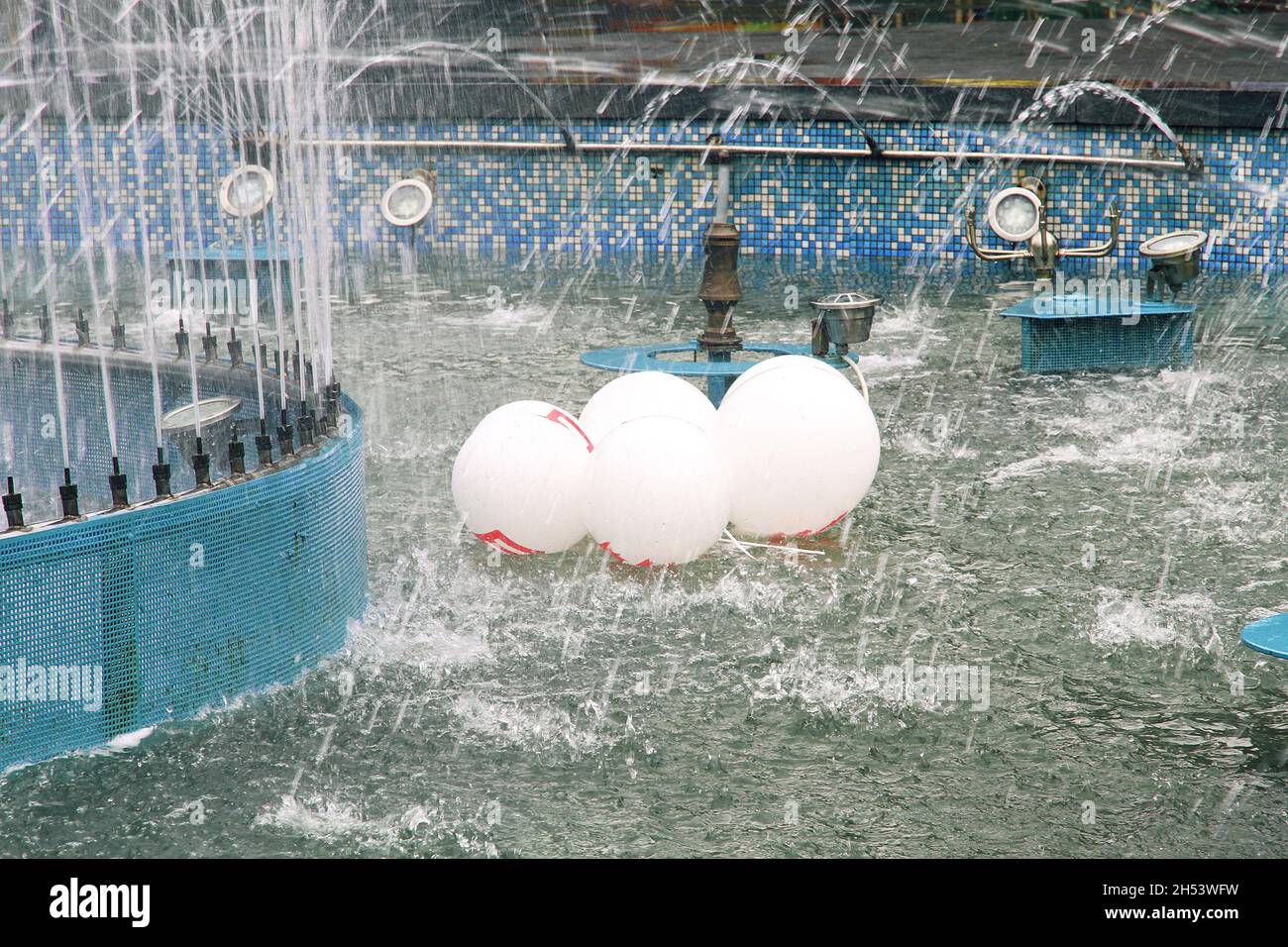 molti palloncini bianchi con un motivo rosso galleggiano nella fontana dopo la festa. ha lasciato cadere le palle nella fontana Foto Stock