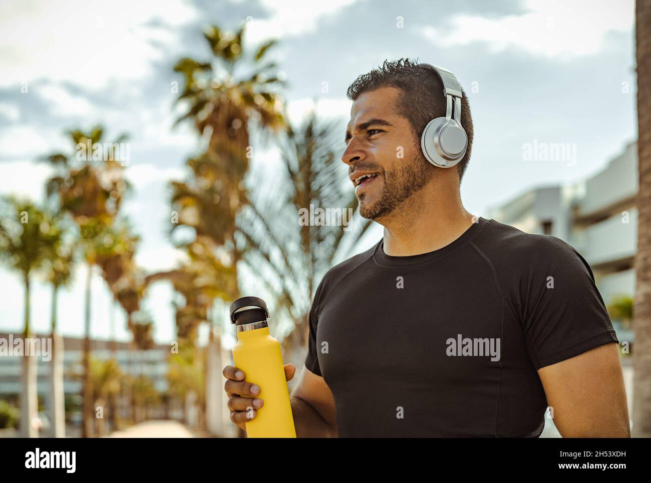 L'uomo ispanico fa jogging e allenamento mentre ascolta la musica con le cuffie wireless all'aperto Foto Stock