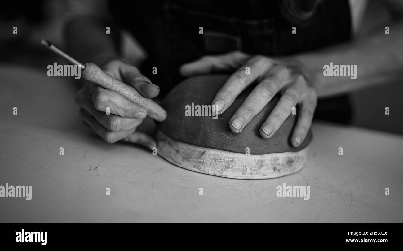 Primo piano su femmina vasaio che modella ciotola di argilla in officina - lavoro artistico e concetto di artigianato creativo - montaggio in bianco e nero Foto Stock