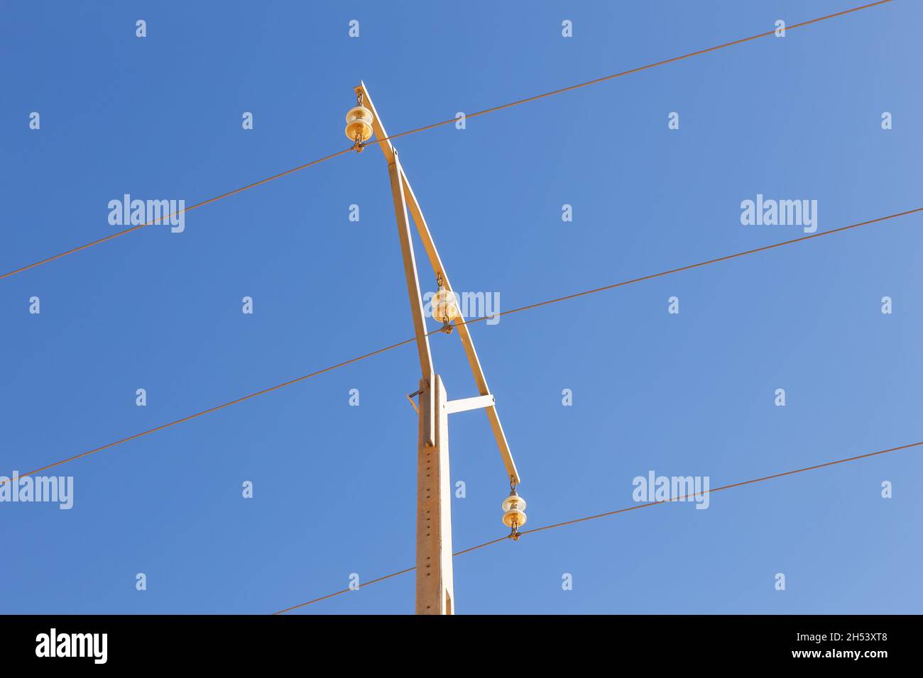 Isolatore sospeso nel deserto del Sahara. Linee elettriche contro il cielo blu Foto Stock