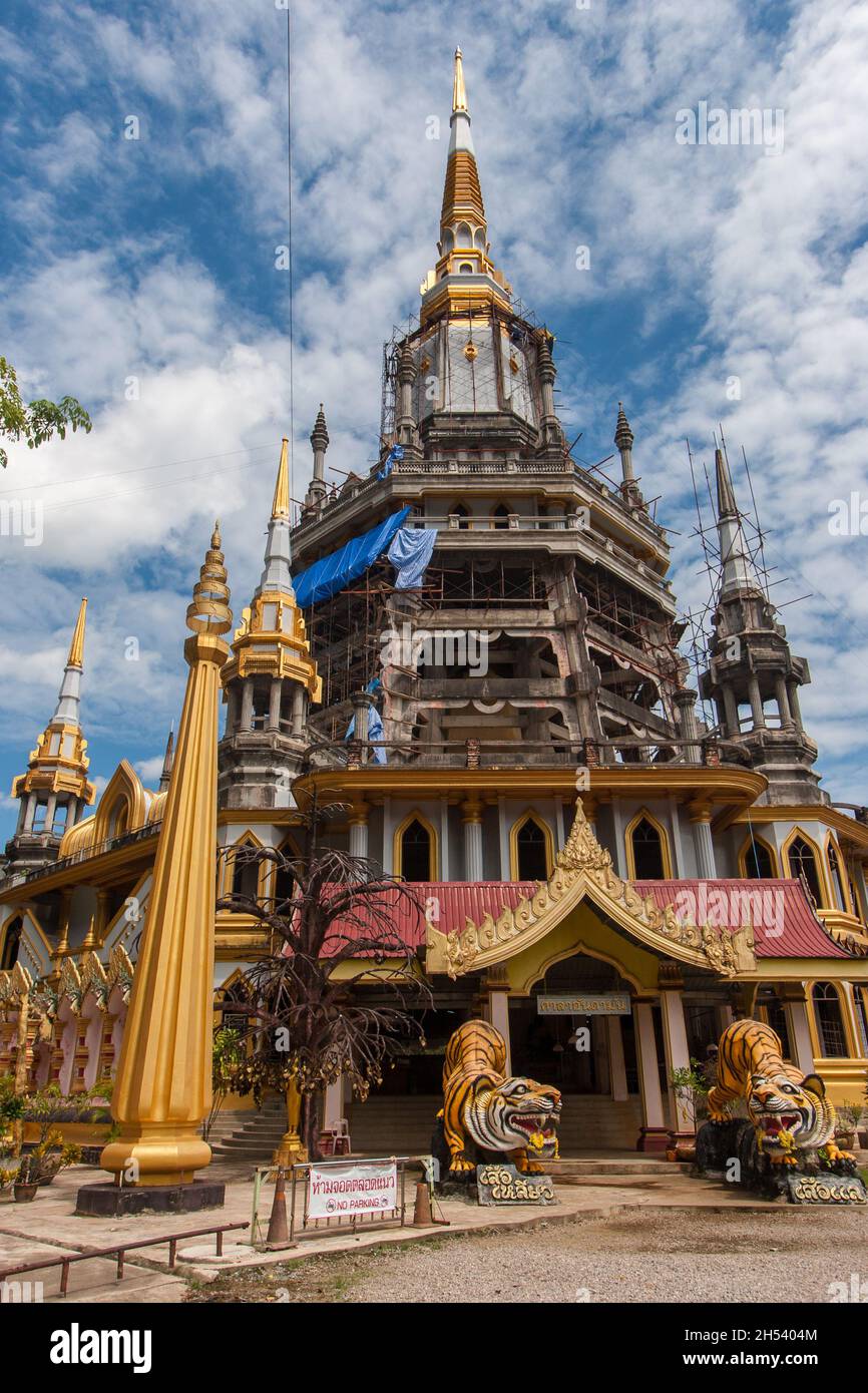 Ingresso alla Grotta della Tigre del Tempio Buddista nella provincia di Krabi in Thailandia. Alte guglie e statue delle tigri. Nuvole nel cielo. Foto Stock