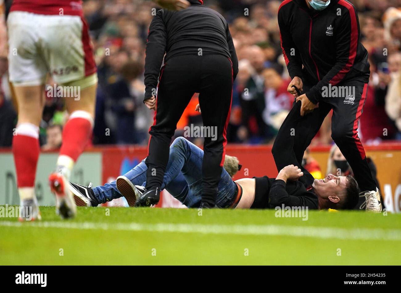 Gli steward rimuovono un fan che invade il campo durante la partita Autumn Internationals al Principality Stadium di Cardiff. Data foto: Sabato 6 novembre 2021. Vedi la storia della Pennsylvania RUGBYU Wales. Il credito fotografico deve essere: David Davies/PA Wire. RESTRIZIONI: L'uso è soggetto a restrizioni. Solo per uso editoriale, nessun uso commerciale senza previo consenso da parte del titolare dei diritti. Foto Stock