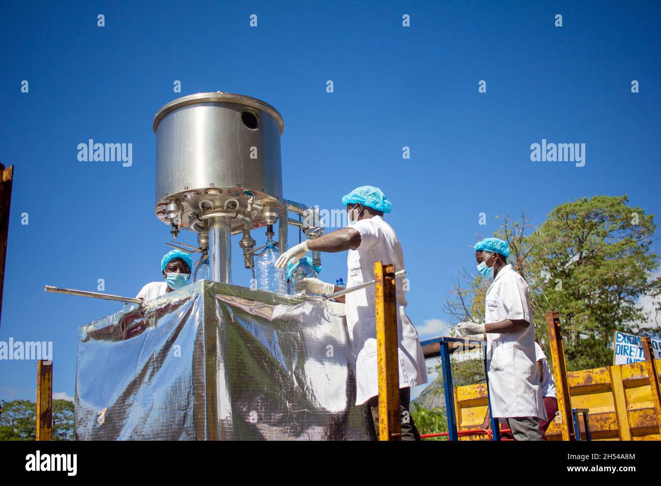 Lavoratori che maneggiano una macchina riempitrice di acqua minerale Foto Stock