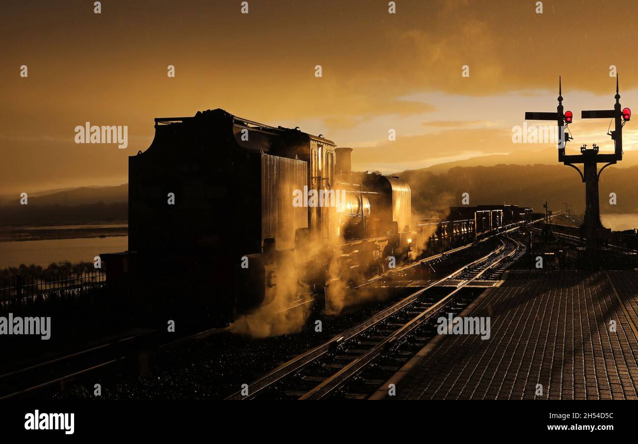 Il sole sorge appena sopra le colline come la pioggia appena comincia e Garratt 130 si ferma a Porthmadog il 3.11.21 Foto Stock