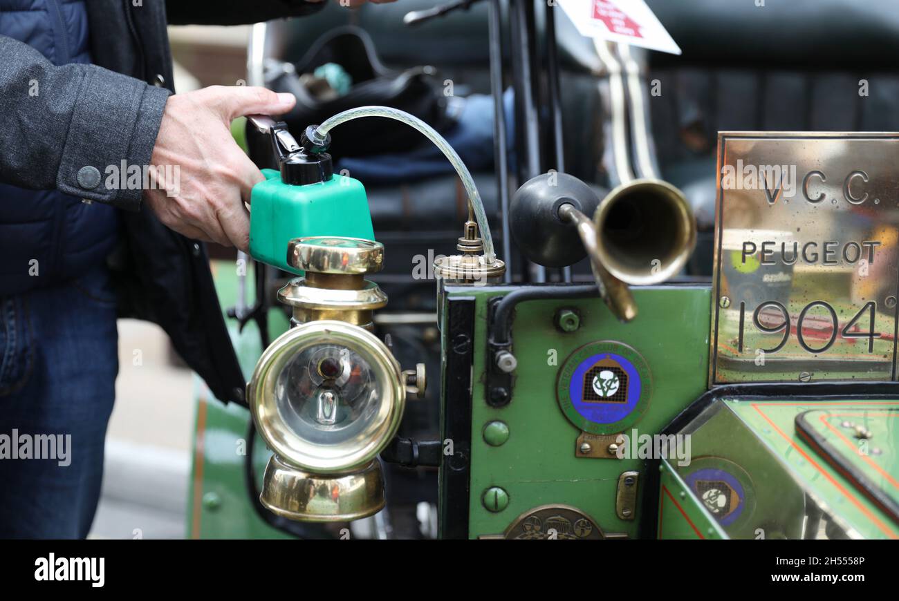 Londra, Gran Bretagna. 6 novembre 2021. Il proprietario rifornisce la sua auto veterana durante l'annuale Regent Street Motor Show a Londra, Gran Bretagna, 6 novembre 2021. Oltre cento auto veterane erano in mostra al Sabato spettacolo, attirando migliaia di appassionati di auto su una strada senza traffico Regent. Credit: Li Ying/Xinhua/Alamy Live News Foto Stock