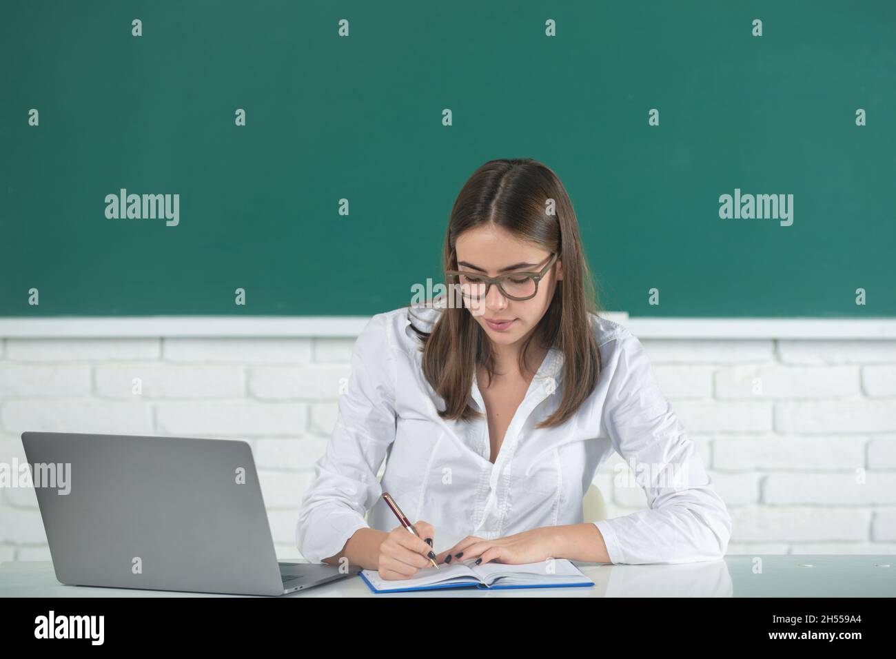 Studente che prepara esami e lezioni di apprendimento in classe scolastica. Freelance femminile o studente con computer portatile. Foto Stock