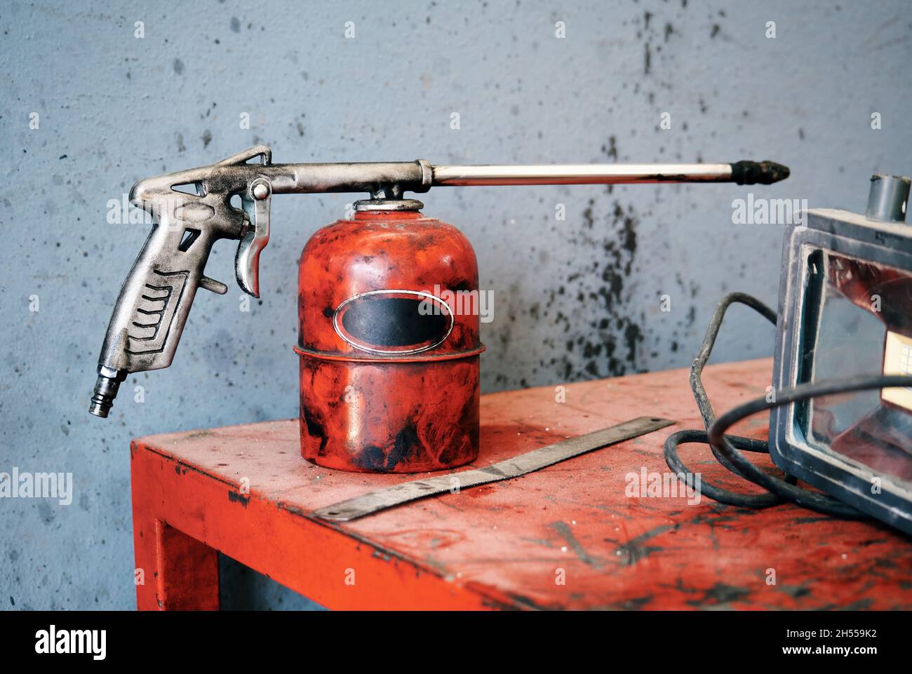 Vecchia pompa oliatore in metallo rosso usurata sul banco di un'officina di riparazione auto. Foto Stock