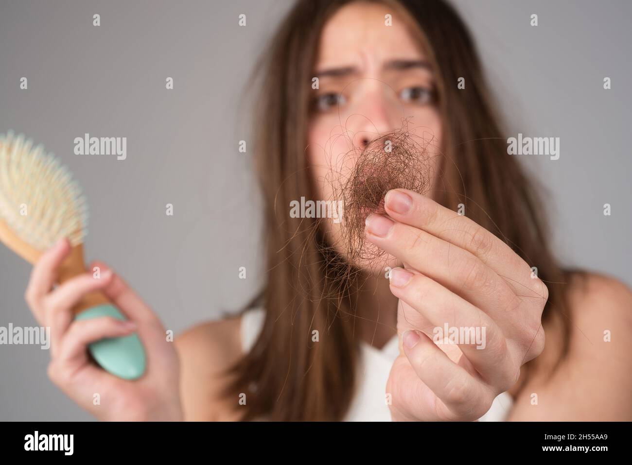 Perdita di capelli nelle donne. La giovane donna è sconvolta a causa della perdita dei capelli. Ritratto di ragazza frustrato con capelli problematici, isolato. Ragazza preoccupata che tiene a lungo Foto Stock