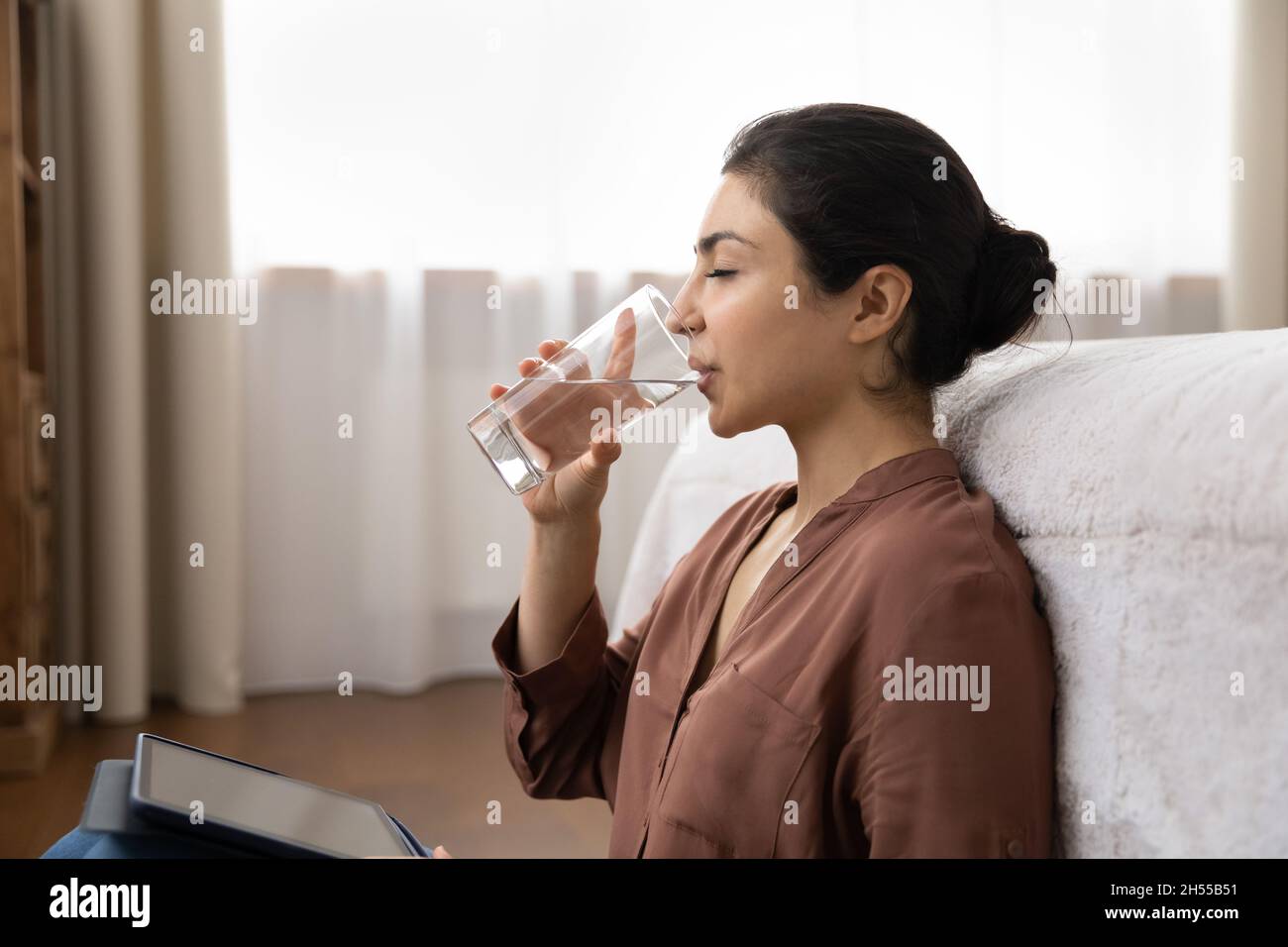 Attraente donna indiana tiene bevande tablet ancora acqua Foto Stock