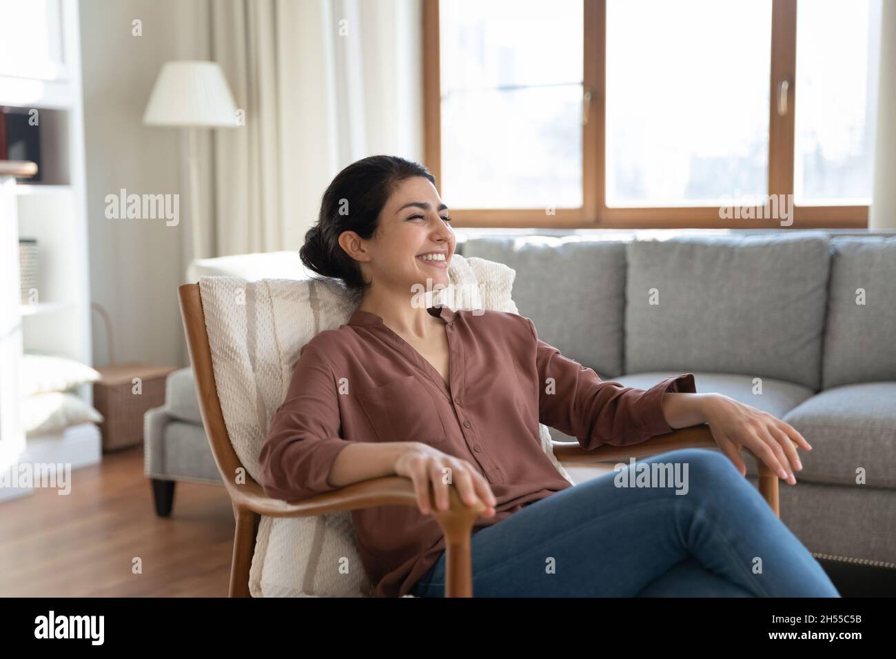 Donna indiana che si rilassa su una comoda poltrona in un accogliente soggiorno Foto Stock