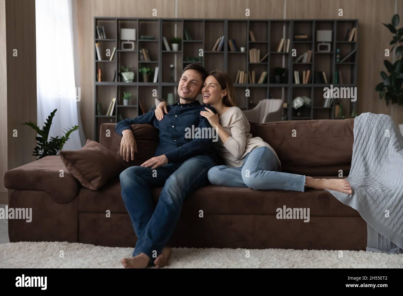 Felice coppia caucasica abbracciare, rilassarsi sul divano, sognare insieme Foto Stock