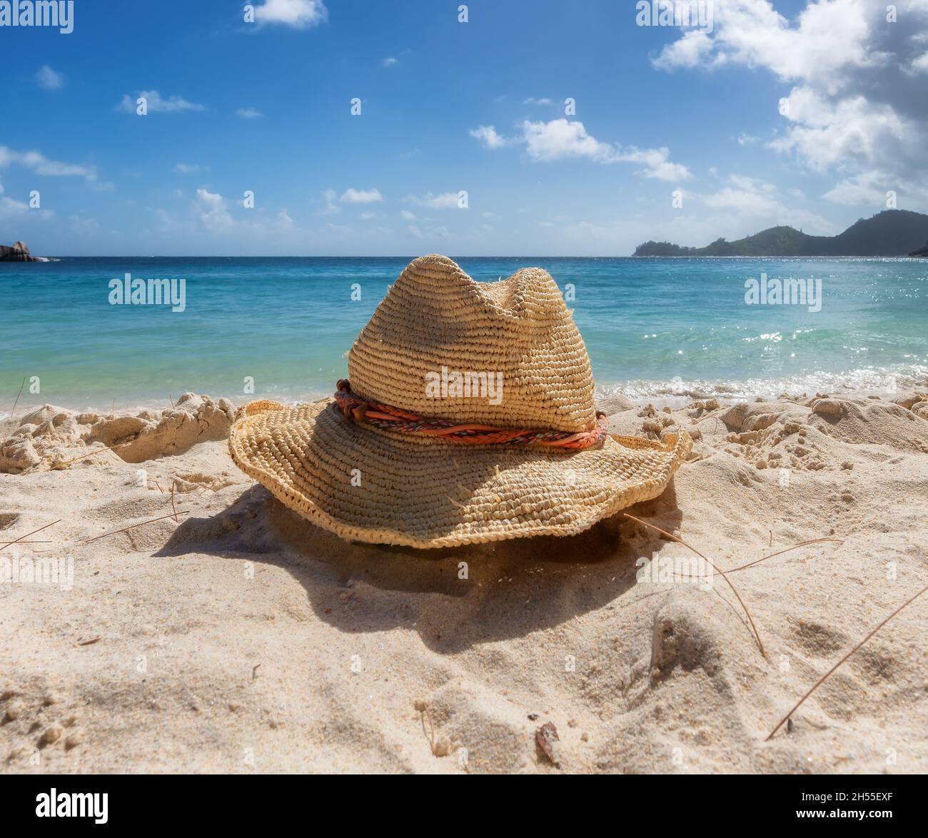 Accessori da spiaggia con cappello di paglia sulla spiaggia sabbiosa tropicale e sul mare blu Foto Stock