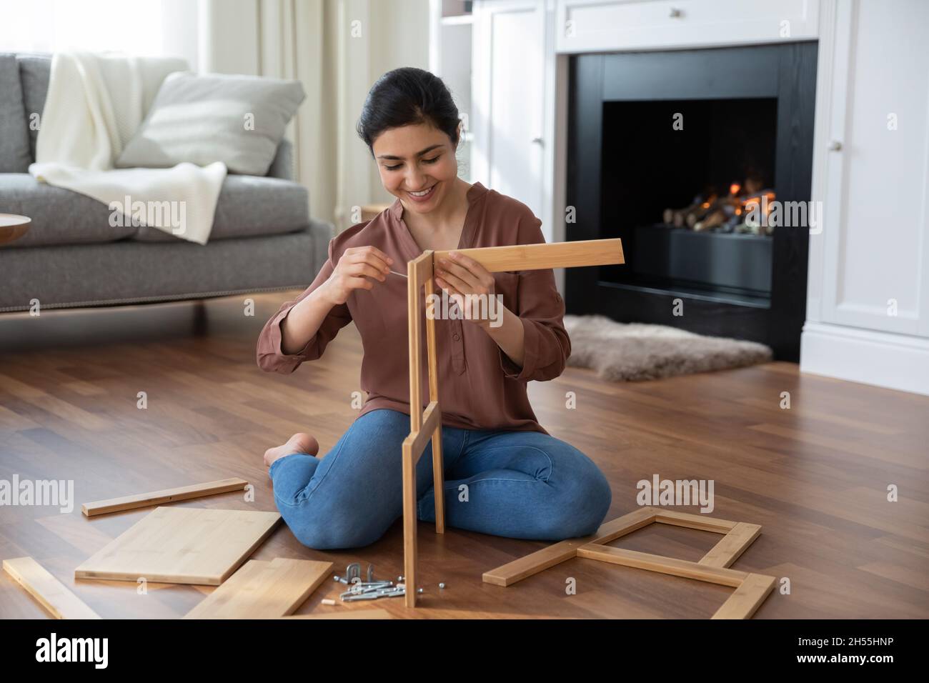 La donna indiana raccoglie nuova sedia che tiene tavole di legno dettagli sedia Foto Stock